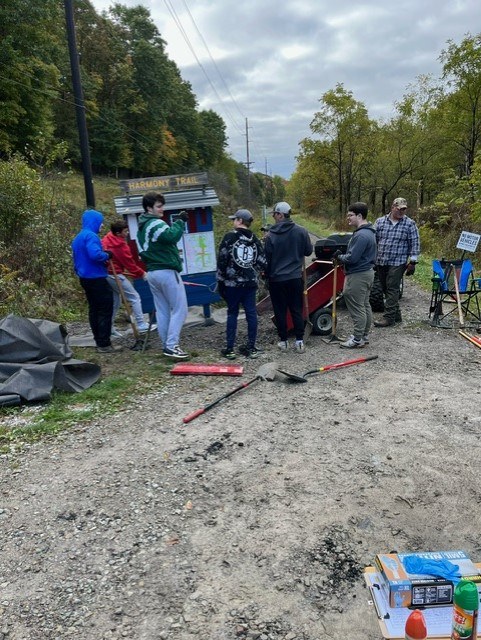 Pine Lacrosse members laying new gravel by the trailhead sign